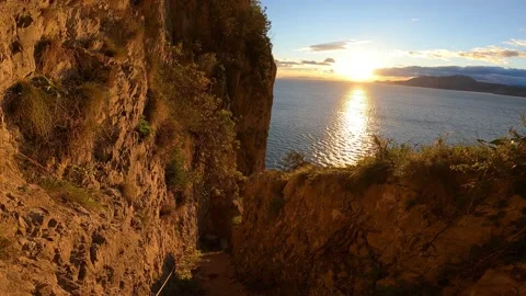 Walking down stairs down a rocky cliff overlooking the sea at sunrise. Plants Stock Footage 141808251