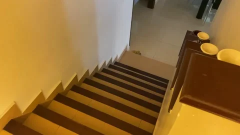 Walking down stairs in home with orange lighting - tilt down Stock Footage 149737455