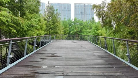 Walking on an elevated wooden boardwalk with railing in an urban park Stock Footage 289621119