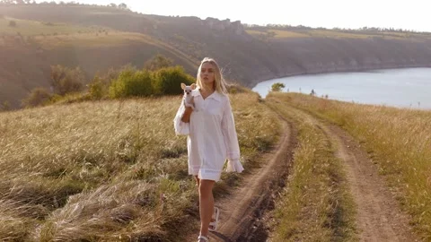 Walking in the field with an incredible landscape view holding a dog Stock-Footage 236559347