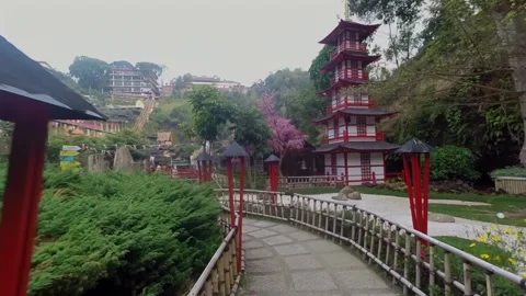 Walking forward on a garden path towards an oriental tower structure Video stock 345645129