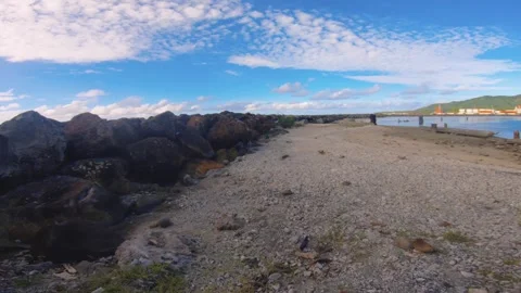 Walking forward low ground view of sandy bay area around Avatiu Harbor along roc Stock Footage 258444585