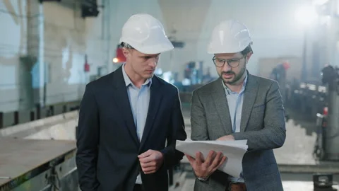 Walking in front of the camera in manufacturing factory two engineers and Stock Footage 262685270