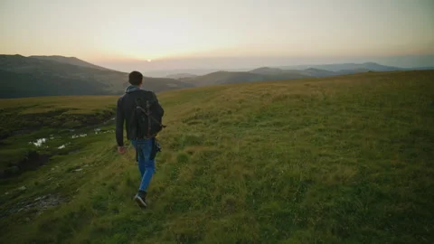 Walking on a grassy hill during sunset in the mountains Stock Footage 345683144