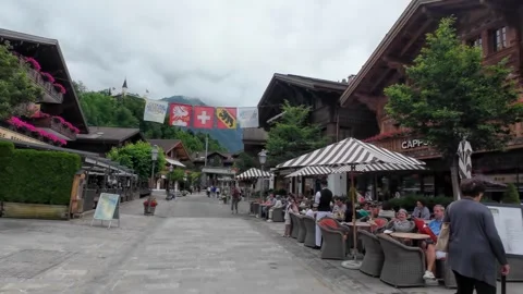 Walking Gstaad Cafe Terrace with Diners and Swiss Flags Stock Footage 340369601