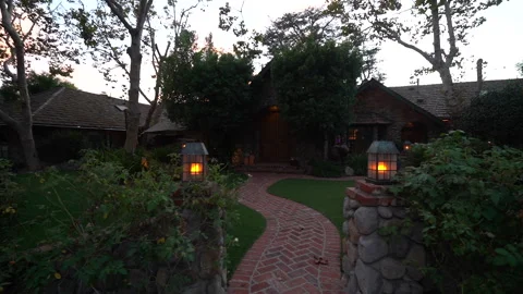 Walking up a lantern-lit brick path to a stone cottage at dusk Stock Footage 345529226
