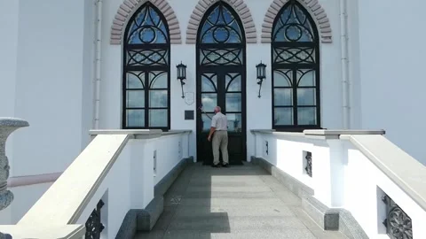 Walking up to a large building with arched windows and a white façade Stock Footage 325525392