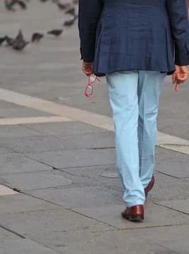Walking man in blue jacket with red eyeglasses in his hand. Stock Photos