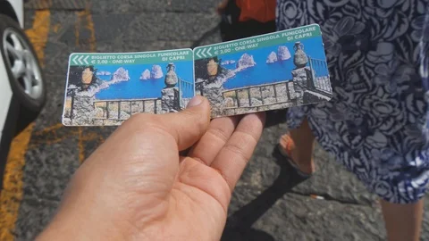 Walking man holds in hand two one way funicular tickets. Capri, Italy. POV shot Stock Footage 99003999