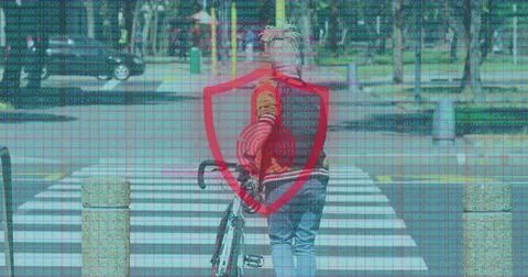 Walking man in red jacket pushing bicycle across zebra crossing, red shield and Stock Photos
