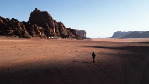 Walking in Marsian desert, bubble camp in background, Wadi Rum, Jordan - 07 Stock Footage 259377217