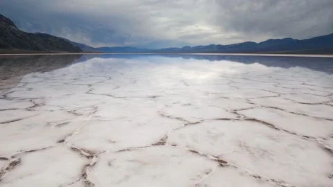 Walking in mirror surface of salt crust formations with water in Badwater Basin Video stock 225328731