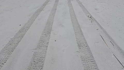 Walking motion perspective over car tire tracks in beach sand Stock Footage 330092218