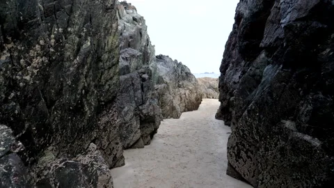 Walking narrow gap between black cliffs on the beach 動画素材 142735041