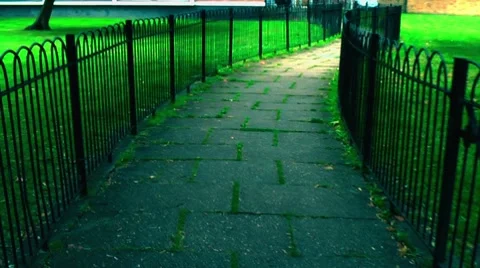 Walking narrow stone path with fence a grass point of view Stock Footage 8663679