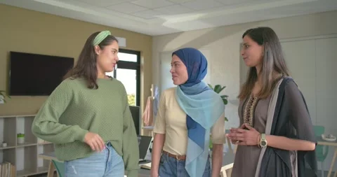 Walking into office sparking desk discussion among diverse female coworkers and Stock Footage 345035659