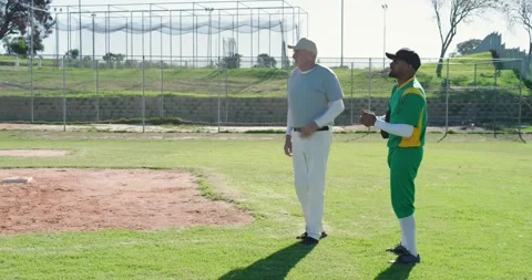 Walking onto outfield, diverse baseball coach and players greeting and pointing Stock Footage 341931488