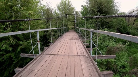 Walking over old bridge across a river in a park. POV shot. Video stock 107607801