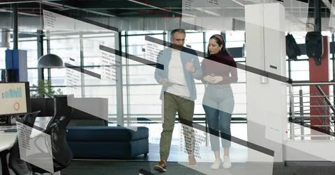Walking pair discussing project in modern workspace, casually dressed with 写真素材