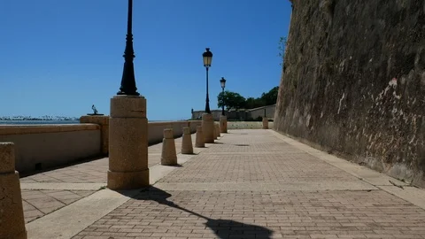 Walking on Paseo la Princesa bayside waterfront walkway under stone city walls. Stock Footage 109187560