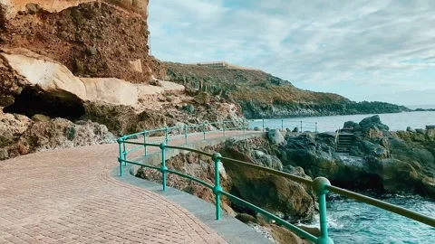 Walking path along the sea. Sheer cliffs above the path. Stock Footage 274452149
