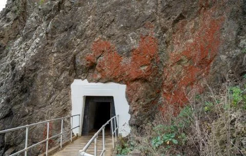 Walking path leading into mountain side tunnel covered in rust Stock Photos