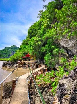 Walking path leads to a waterfront building surrounded by rocks and greener.. Stock Photos