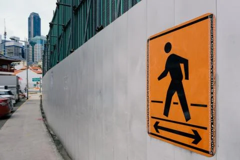Walking path sign on under construction wall for pedestrians in city Stock Photos