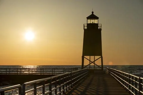 Walking path to silhouette of light house at sunset Stock Photos