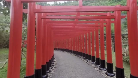 Walking path through a corridor of red pillars and arches in a park Stock Footage 345654370