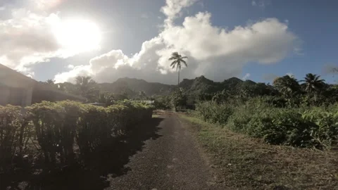 Walking on a pave dirt narrow primitive road passing by a house in neighborhood Stock Footage 233603133