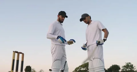 Walking onto pitch stumps at dusk, two male batsmen tapping bats adjusting Stock Footage 341240252