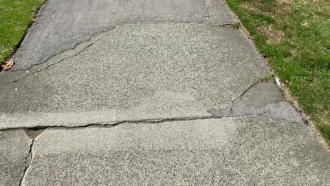 Walking POV on concrete pathway cracks and grass Stock Footage 283291898