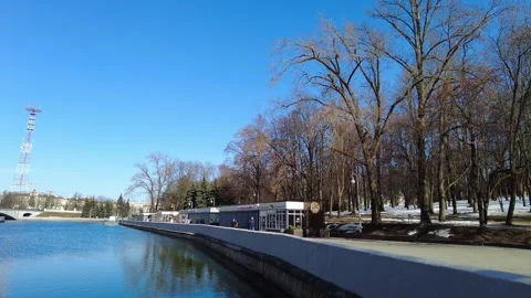 Walking by the river in a park with trees and buildings in early spring time Stock Footage 333443633