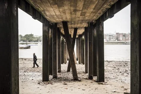 Walking on a River Thames beach underneath a pier on the banks of the River Stock Photos