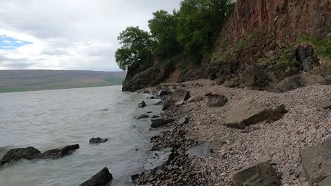 Walking on the rocky beach below the cliff Stock Footage 168838116