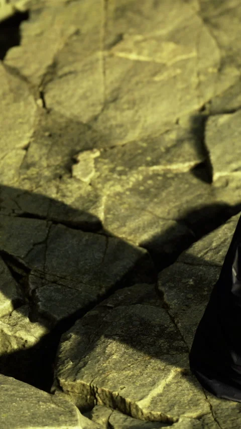 Walking on rocky terrain while collecting items in a black bag during the day Stock Footage 334725314