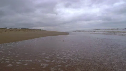 Walking in the sand of an empty lonely beach bordering the sea waves Stock Footage 133608142