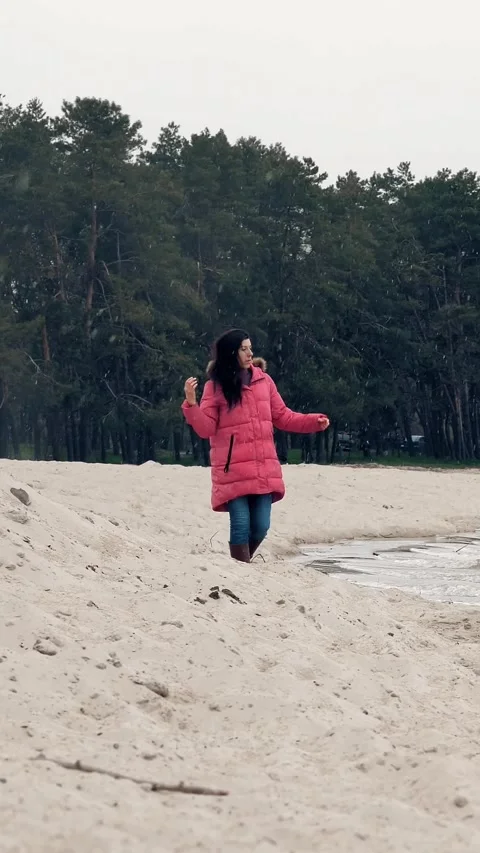 Walking by the sea in winter. Sad, alone woman is watching on sea or river waves Stock Footage 317850036
