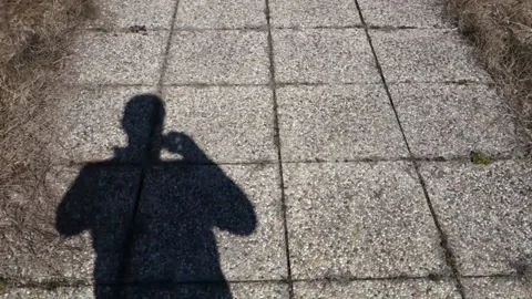A walking shadow of a man on a stone pavement Stock Footage 172383950