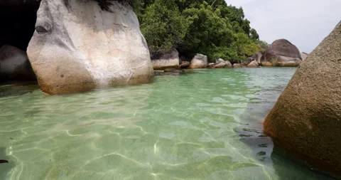 Walking in shallow calm and clear water between large rocks, Perhentian Islands Stock Footage 314637716
