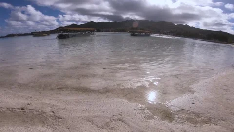 Walking into shallow calm lagoon from white sandy beach look out to empty touris Stock Footage 250402243