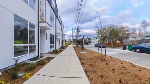 Walking on sidewalk in front of a row of condominiums Stock Footage 274515158