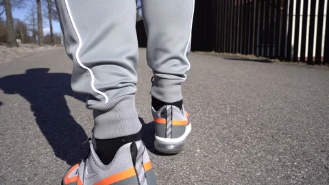 Walking on a sidewalk in stylish orange nike sneakers Stock Footage