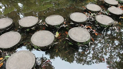 Walking on the stone slabs across the pond Stock Footage 28664652