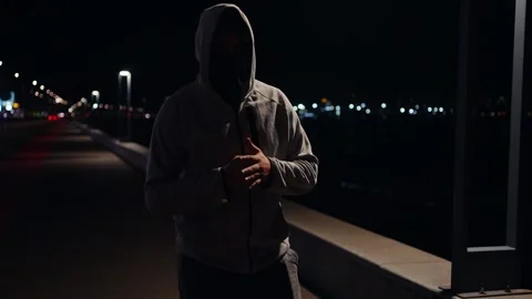 Walking thief or robber in a mask hiding his face from cameras and a hood Stock Footage 249534710