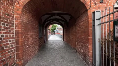 Walking Through Brick Archway Toward Historic Waterfront Bridge Stock Footage 340505661