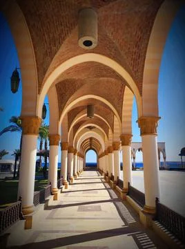 Walking through a corridor with arches and columns by the beach on a sunny .. Stock Photos
