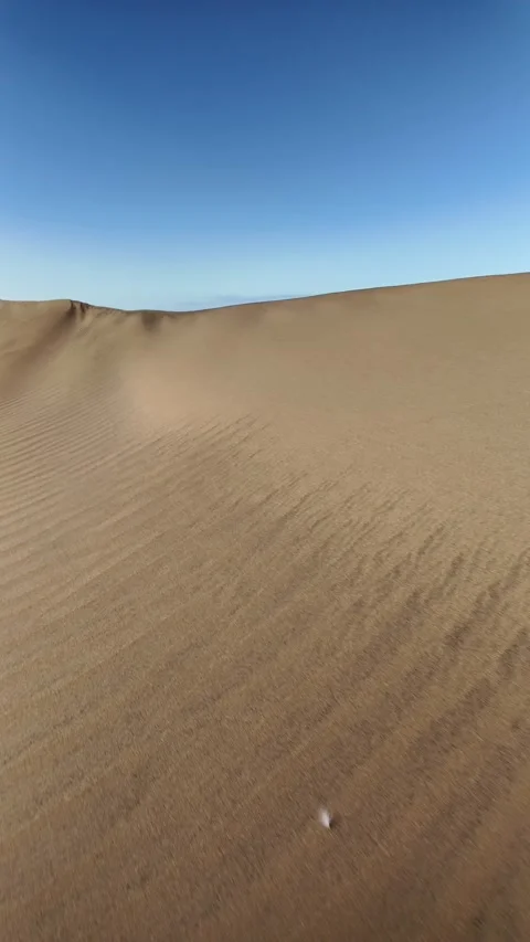 Walking through desert sand dunes under a clear blue sky Stock Footage 346177726