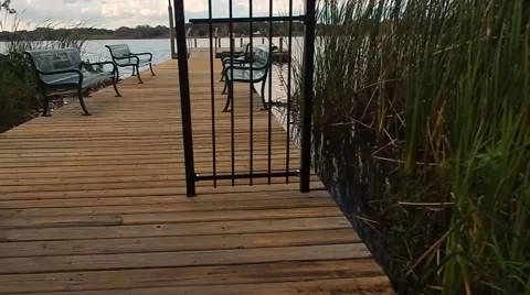 Walking through gate on dock, looking over bench to lake Stock-Footage 45603761